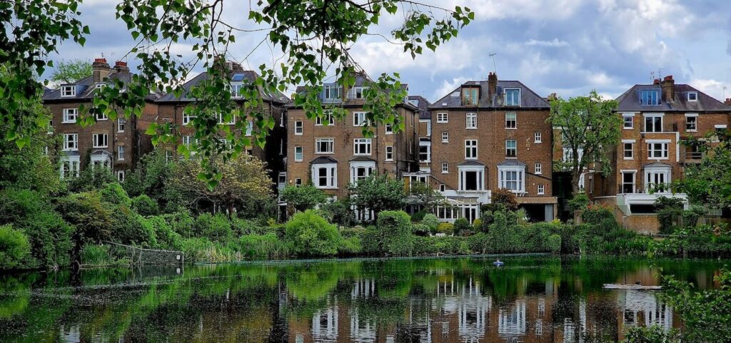 Scenic pond and Victorian mansion surrounded by mature trees in Hampstead, London